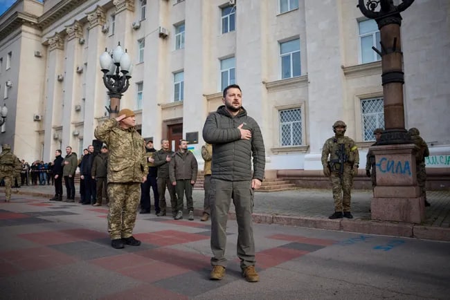Xersonda madhiya kuylayotgan Zelenskiy va Ukraina bayrog‘ini ko‘tarayotgan askar. Urushning 264-kunidan fotoreportaj